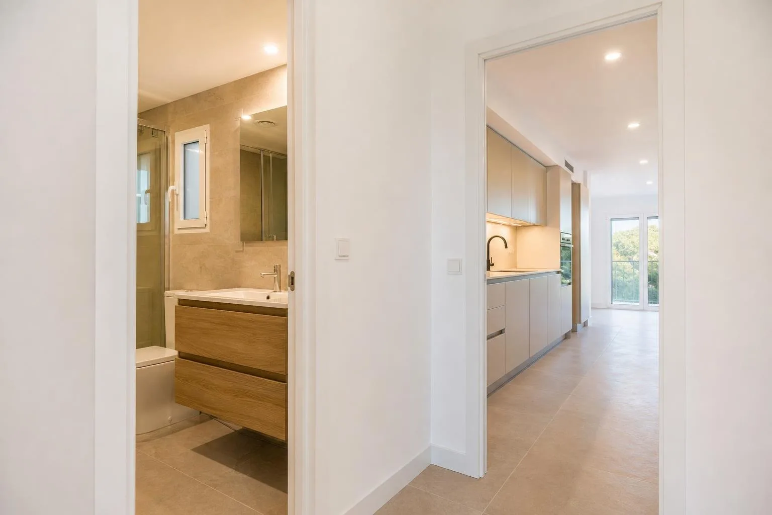 Pasillo de una vivienda con baño y cocina reformados al fondo