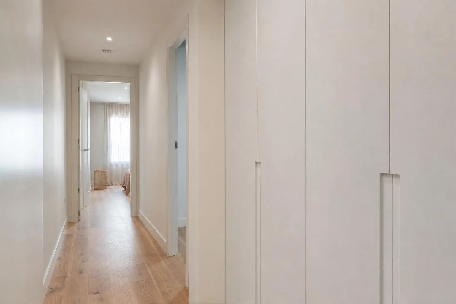 Pasillo de vivienda reformado con armario empotrado y suelo de madera